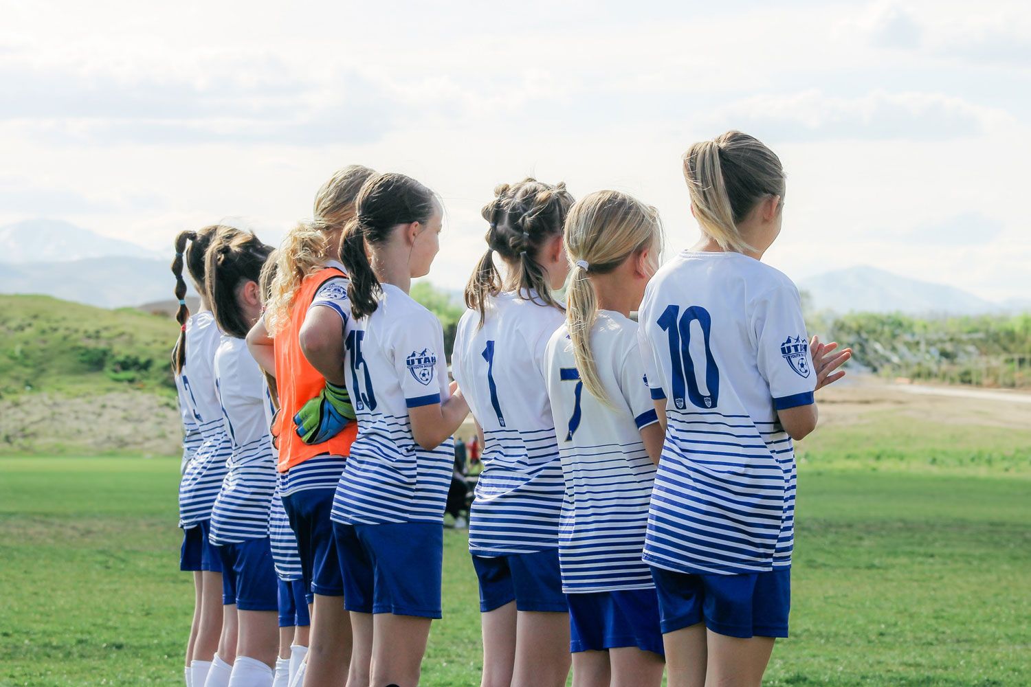 Girls soccer team lined up in a row looking onto the field